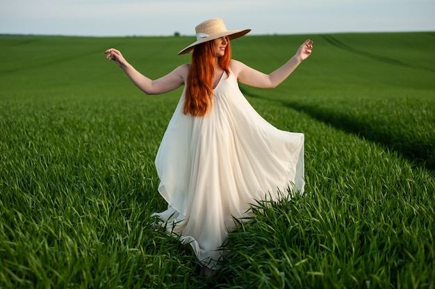 Mulher em um vestido longo branco em um campo verde