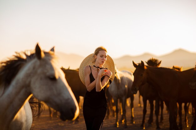 Mulher em um vestido preto entre cavalos selvagens