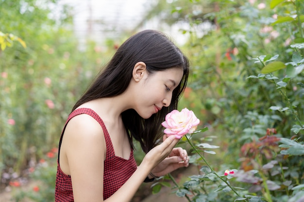 Mulher em um vestido vermelho, posando em um jardim de rosas.