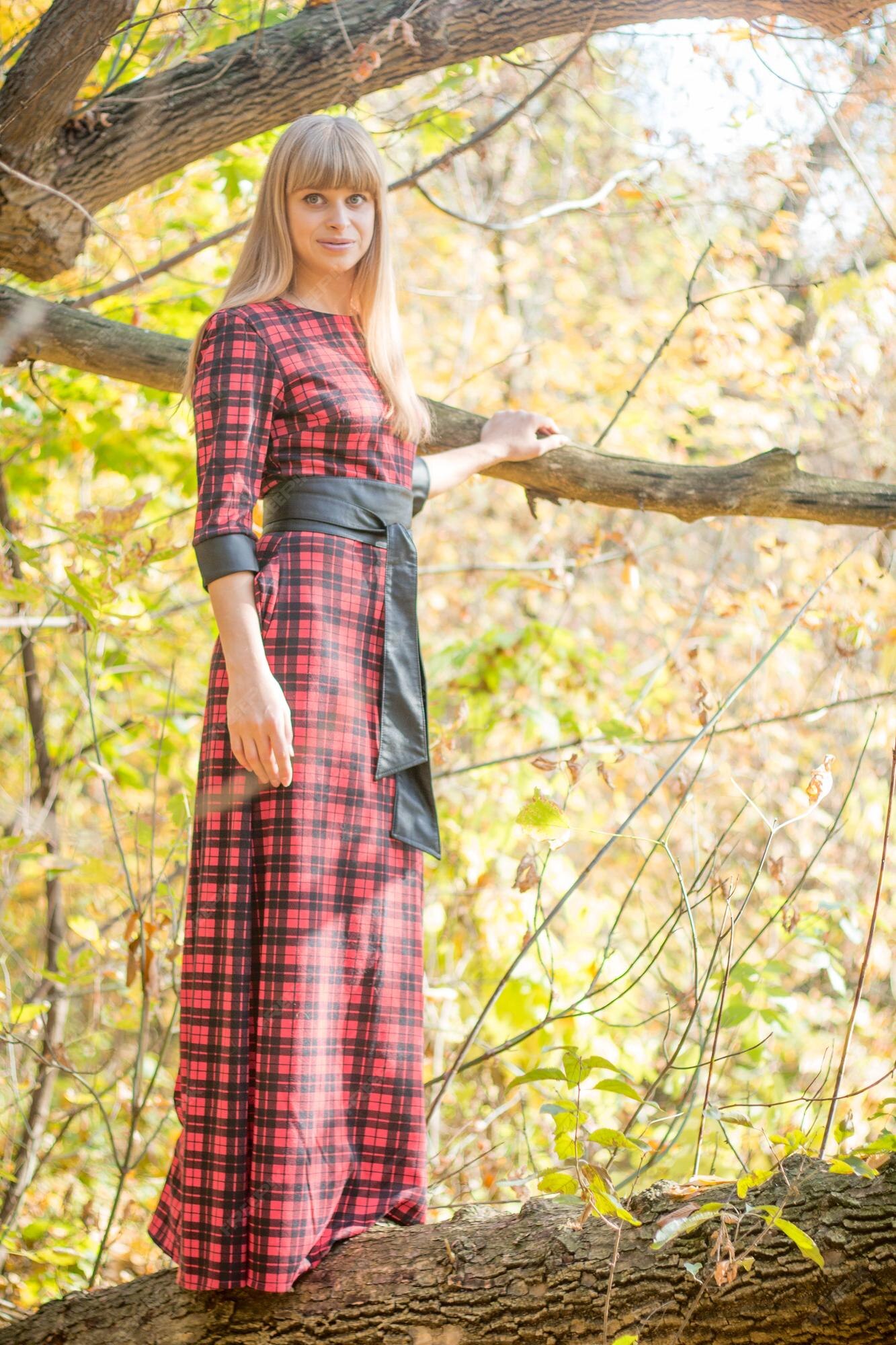 Foto Uma menina em um vestido xadrez segurando um telefone celular – Imagem  de Profundidade de campo