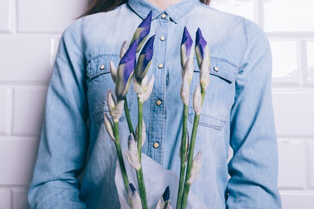 Mulher em uma camisa jeans segurando um buquê de íris de flores não cultivadas