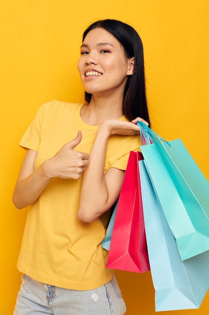 Mulher em uma camiseta amarela com fundo isolado de sacos de compras multicoloridos inalterado