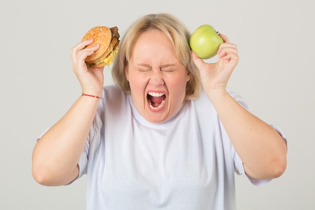 Mulher em uma camiseta branca com um hambúrguer e uma maçã