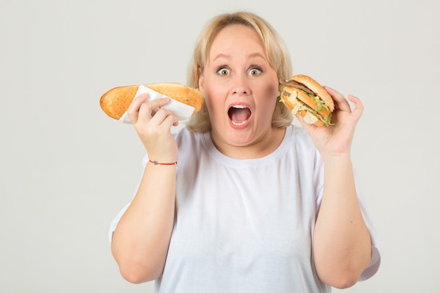 Mulher em uma camiseta branca com um sanduíche e um hambúrguer