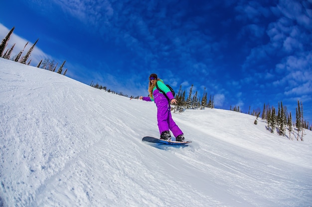 Mulher em uma prancha de snowboard nas montanhas Sheregesh.