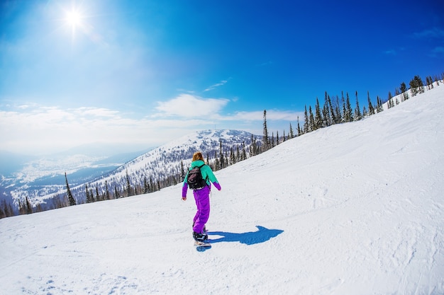 Mulher em uma prancha de snowboard nas montanhas