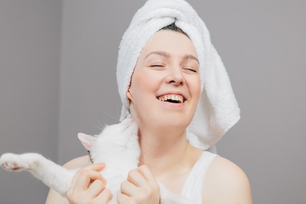 Foto mulher em uma toalha na cabeça com um gato em uma luz