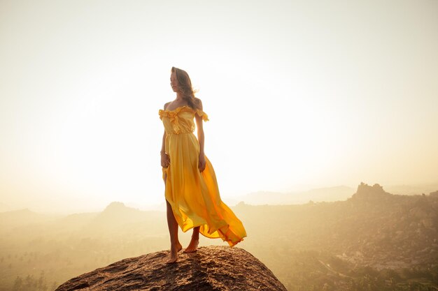 Mulher em vestido longo de seda amarela nas colinas de MAatanga em Hampi karnataka Índia