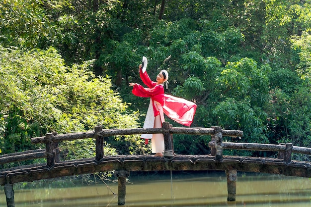 Foto mulher em vestido tradicional dançando com handfan na foto da ponte