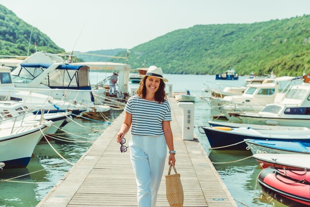 Mulher em vista de luxo de moda branca andando por barcos de doca no fundo