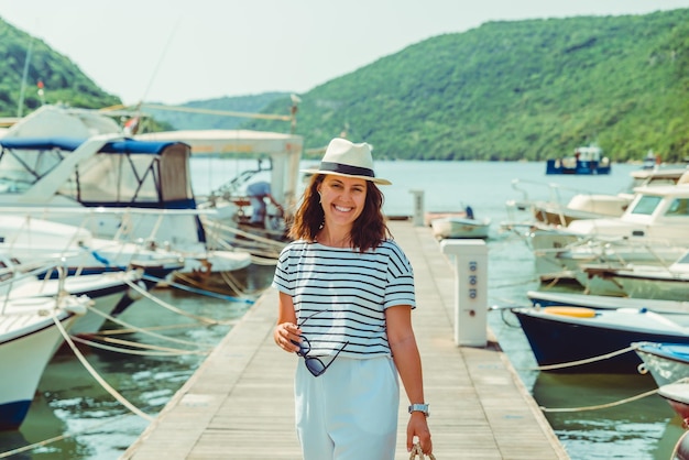 Mulher em vista de luxo de moda branca andando por barcos de doca no fundo