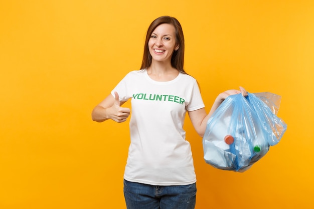 Mulher em voluntário de t-shirt, saco de lixo isolado em fundo amarelo. Ajuda de assistência gratuita voluntária, graça de caridade. Problema de poluição ambiental. Pare o conceito de proteção ambiental de lixo natural.