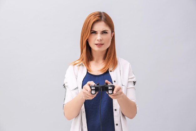 Mulher emocional com controlador de videogame em fundo cinza