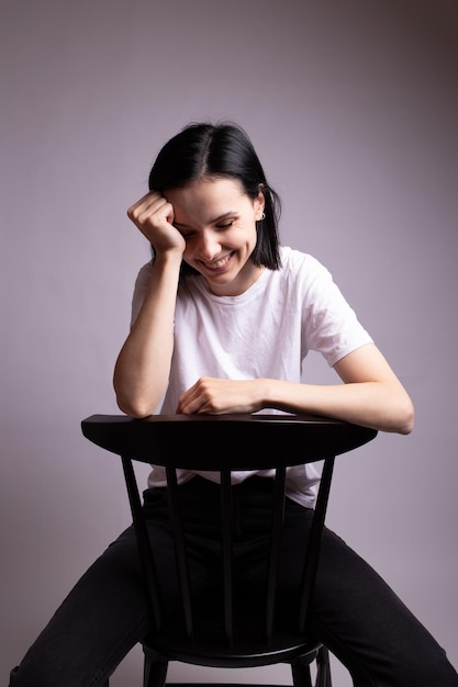 mulher emocional em camiseta branca se senta em uma cadeira