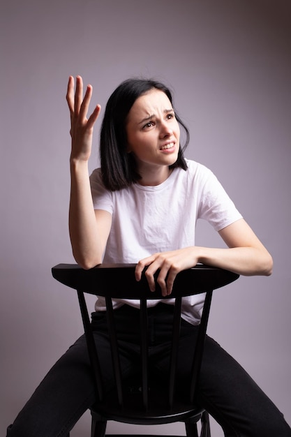 mulher emocional em camiseta branca se senta em uma cadeira