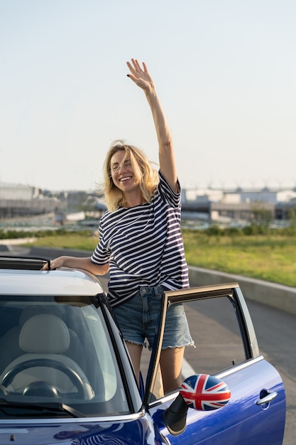 Mulher empolgada olhando do banco do motorista de um carro novo, feliz por comprar ou alugar um automóvel