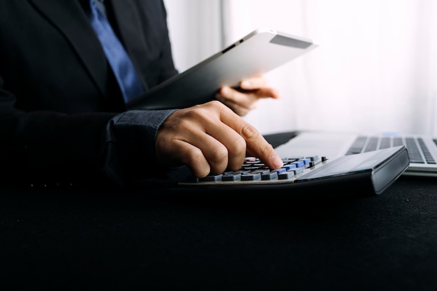 Mulher empreendedora usando uma calculadora com uma caneta na mão calculando despesas financeiras em home office