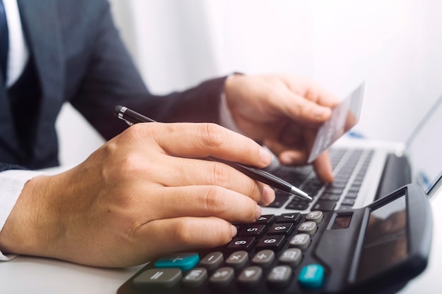 Mulher empreendedora usando uma calculadora com uma caneta na mão calculando despesas financeiras em home office