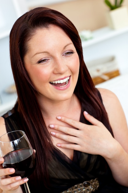 Mulher encantada segurando um copo de vinho em casa