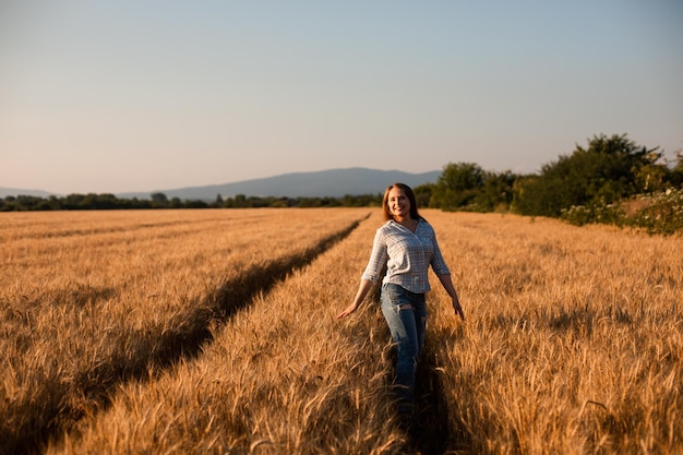 Mulher encantadora, aproveitando o momento andando no campo de grãos