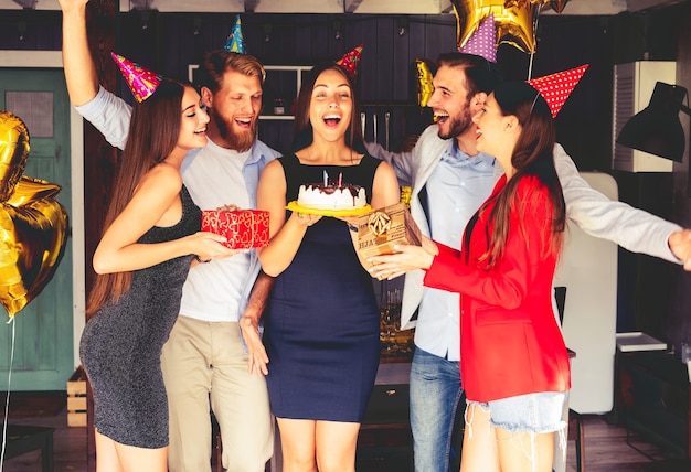 Mulher encantadora soprando velas no bolo de aniversário depois de fazer seu pedido na festa