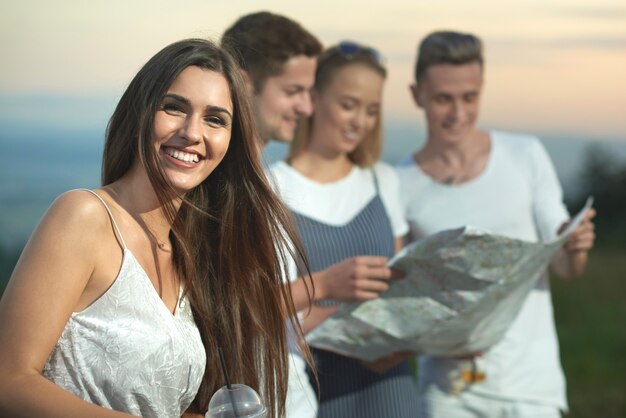 Mulher encantadora sorrindo e enquanto amigos segurando o mapa.