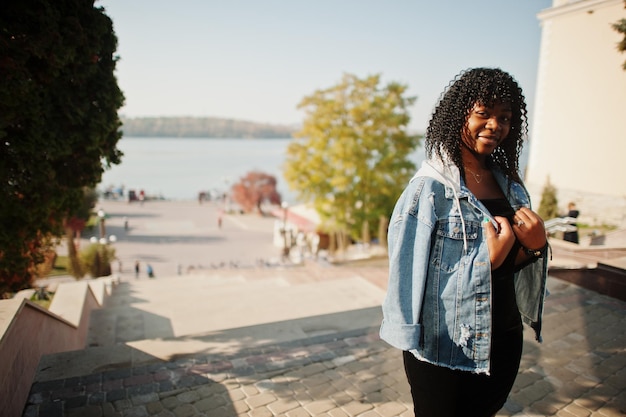 Mulher encaracolada afro-francesa elegante posou no dia do outono em jaqueta jeans Modelo feminino africano negro