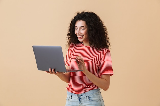 Foto mulher encaracolada muito jovem incrível usando o computador portátil.