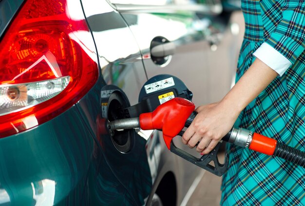 Foto mulher enche gasolina em seu carro em um posto de gasolina