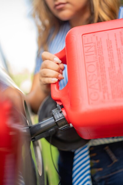 Foto mulher enchendo seu carro de gasolina com um galão vermelho