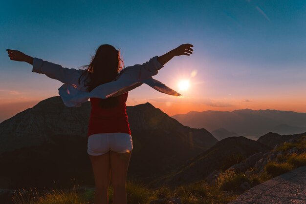 Mulher encontrando o pôr do sol no pico da montanha do parque nacional de lovcen em montenegro