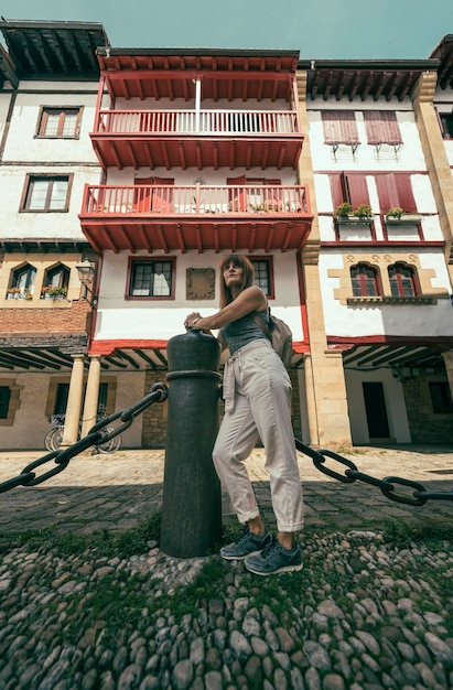 Mulher encostada em um poste de ferro em frente a um prédio vermelho