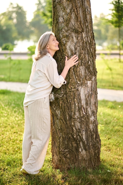 Mulher encostada em uma árvore no parque verde