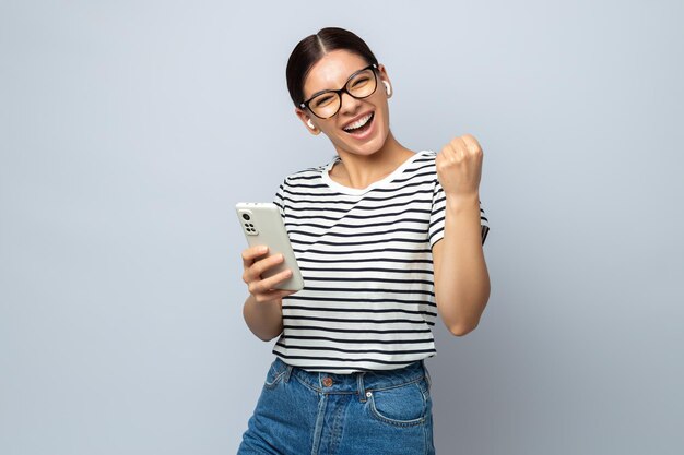 Mulher energizada com fones de ouvido segurando um telefone e ouvindo música curtindo totalmente