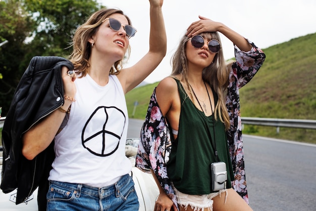 Mulher engate caminhadas no lado da rua perto do carro quebrado