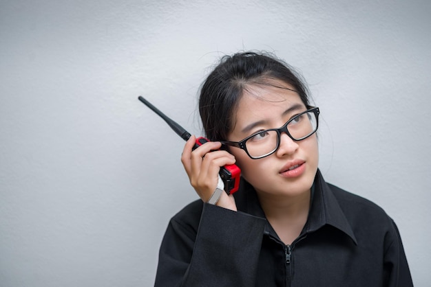 Mulher engenheira asiática usando óculos usando comunicação de rádio em fundo branco técnico tailandês usa walkie talkie para trabalhar