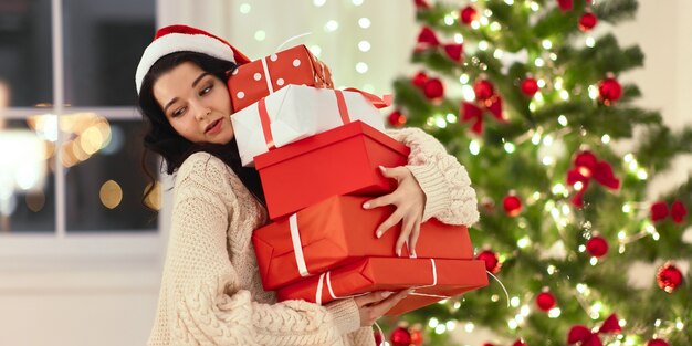 Mulher engraçada do papai noel com presentes em casa