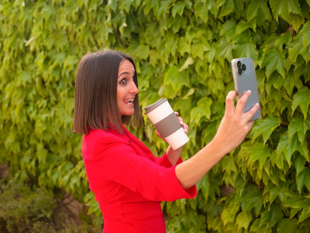 Mulher engraçada tomando selfie com café para viagem no jardim