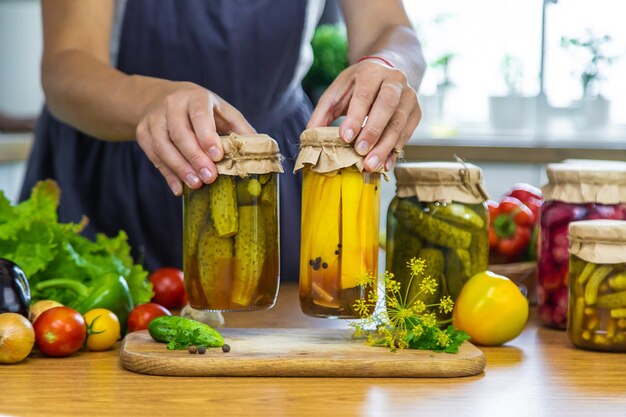 Mulher enlatando legumes em frascos na cozinha Foco seletivo