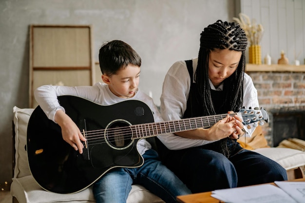 Mulher ensinando um menino a tocar guitarra Foto de estoque