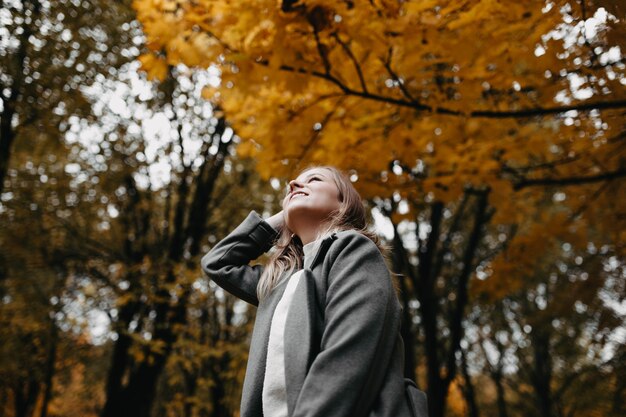 mulher entra ao longo do beco de outono do parque uma garota com um casaco cinza