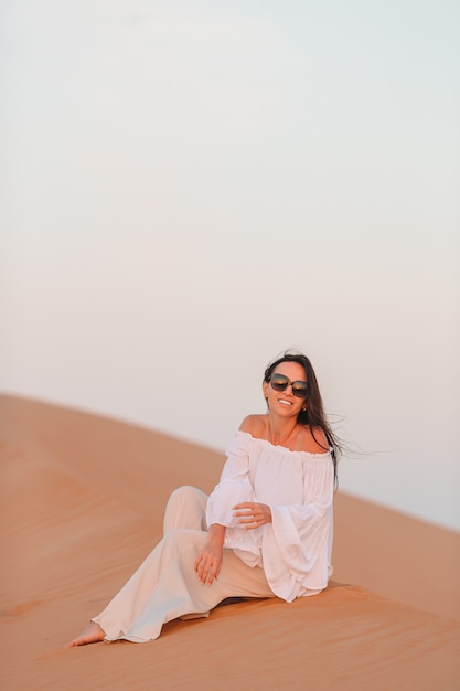 Mulher entre dunas no deserto nos Emirados Árabes Unidos