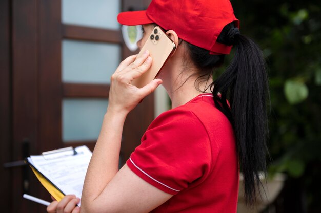 Foto mulher entregadora de tiro médio falando ao telefone