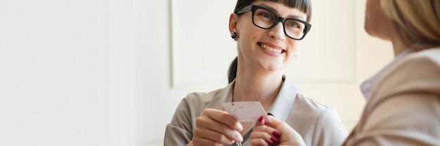 Mulher entregando um cartão de visita em uma reunião