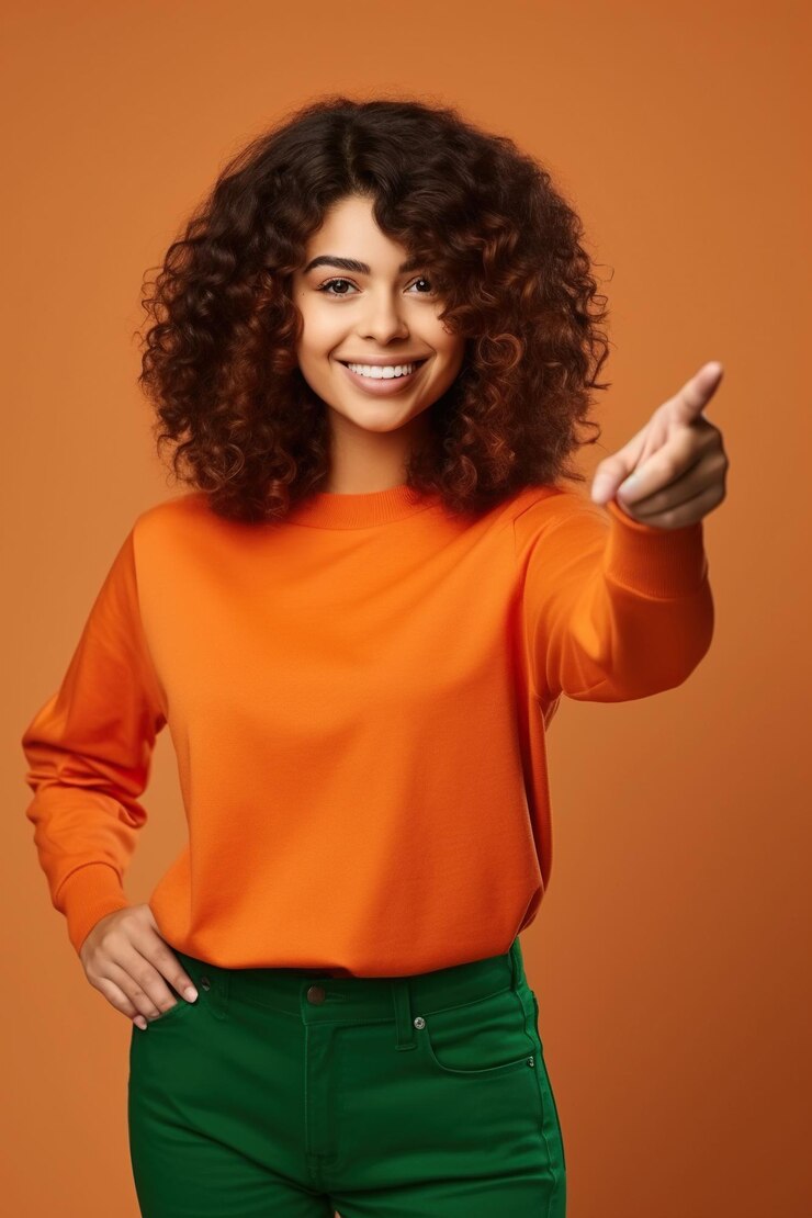 Mulher entusiasmada positiva vestindo camisa verde olhando para o espaço vazio isolado fundo de cor laranja