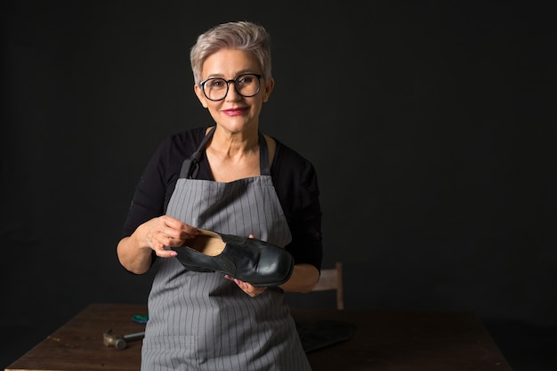 Mulher envelhecida elegante de óculos em um fundo preto