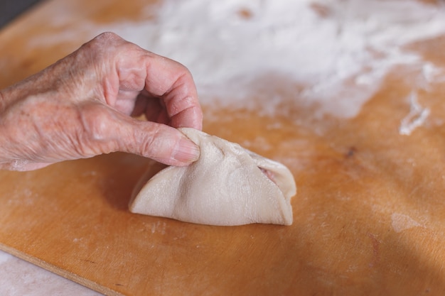 Mulher envelhecida está cozinhando manti.