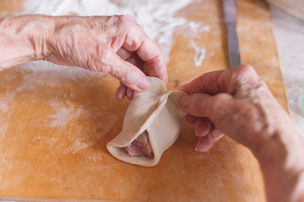 Mulher envelhecida está cozinhando manti.