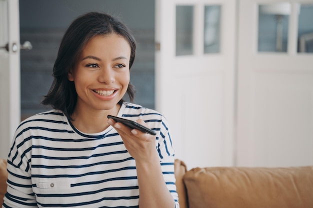 Mulher envia mensagem de voz por smartphone usa viva-voz desfrutando de comunicação online em casa