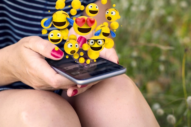 Mulher enviando emoticons smartphone na grama